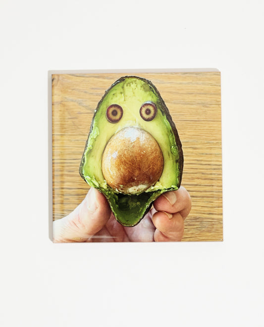 Carreau de faïence imprimée d'une photo de l'artiste Olaf Breuning représentant un visage sur un avocat et de la nourriture. Celui-ci peut être intégré à une faïence de cuisine ou accroché dans la maison.