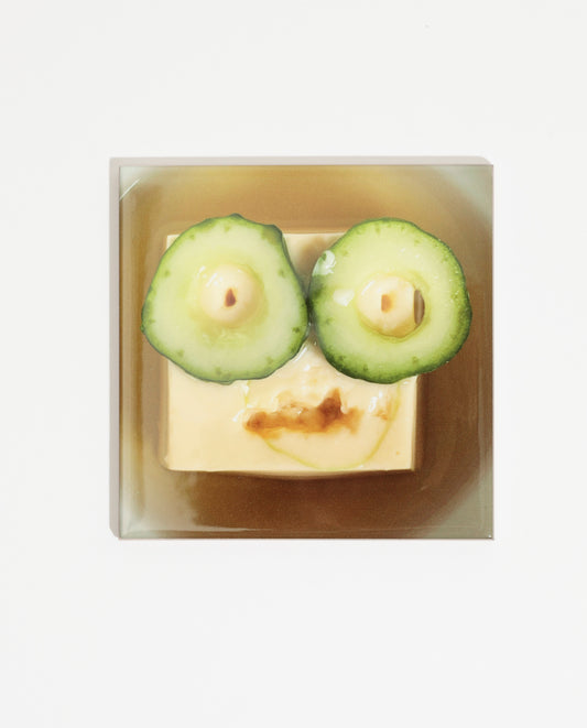 Carreau de faïence imprimée d'une photo de l'artiste Olaf Breuning représentant un visage sur un morceau de tofu avec des yeux en rondelles de concombre. Celui-ci peut être intégré à une faïence de cuisine ou accroché dans la maison.